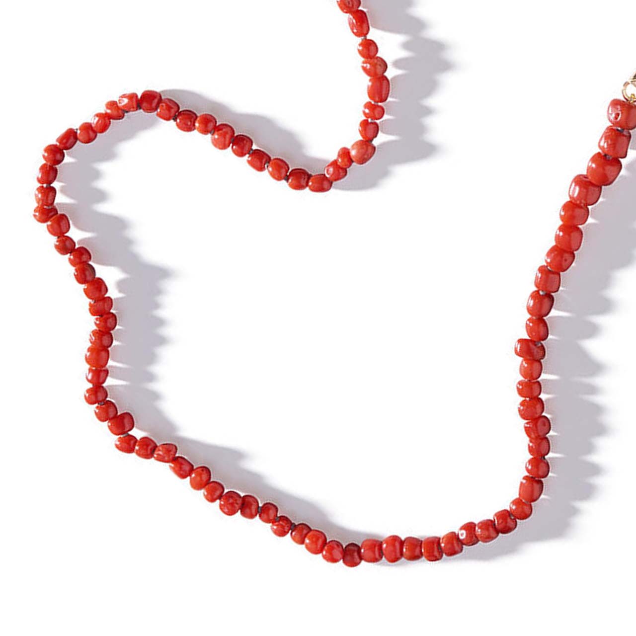 collar de coral rojo sobre un fondo blanco. Un precioso collar de piedras de coral 